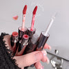 Hand holding multiple lip products with a neutral background