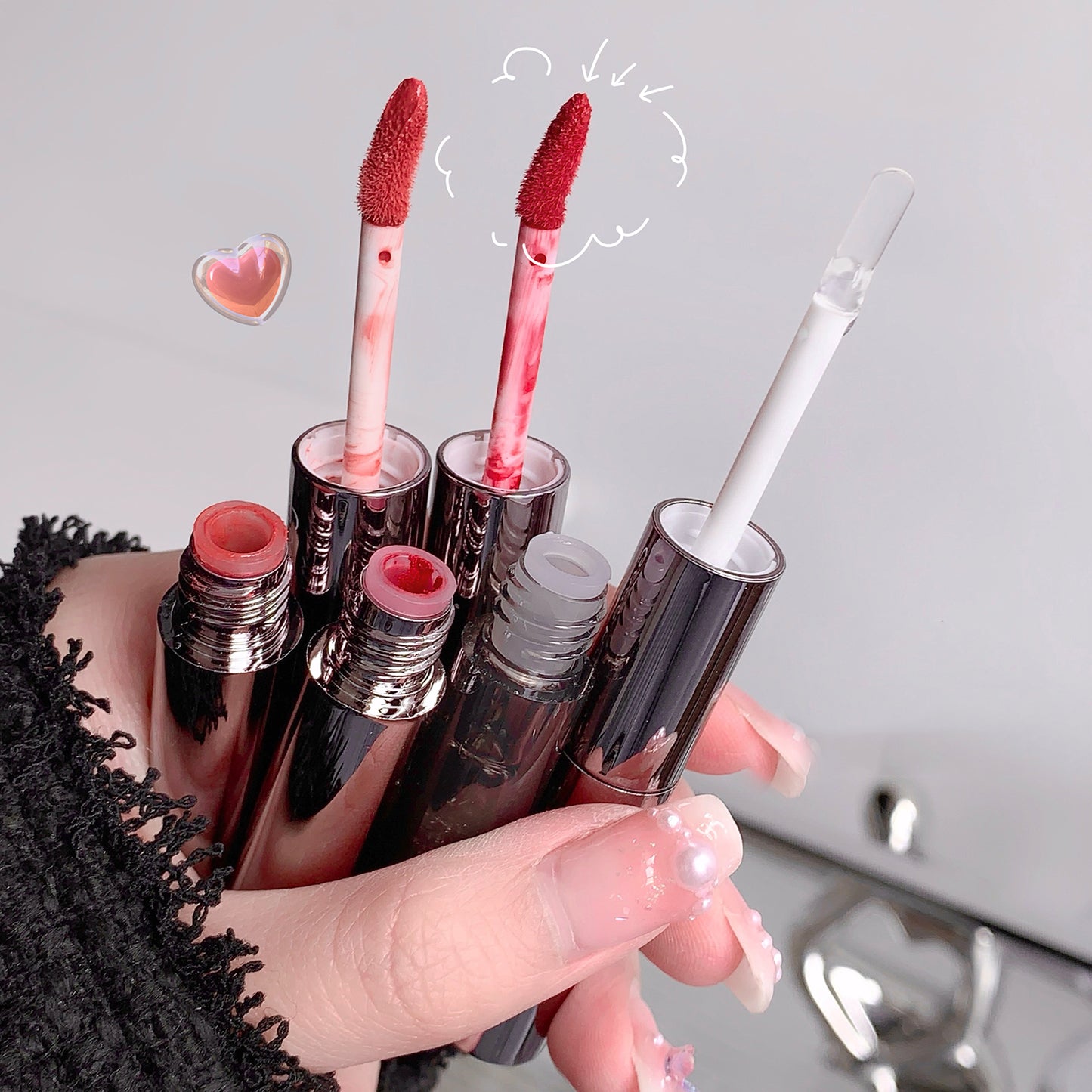 Hand holding multiple lip products with a neutral background