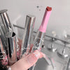 Hand holding a pink and silver lipstick with a starry background