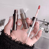 Hand holding three cosmetic products with visible branding against a neutral background