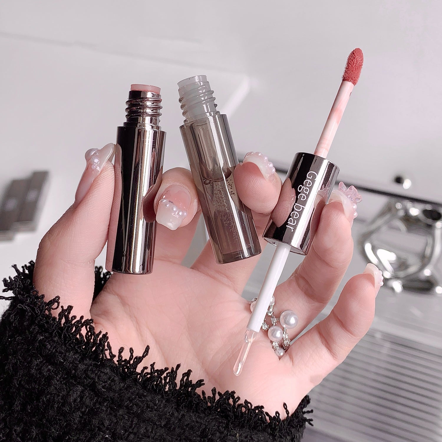 Hand holding three cosmetic products with visible branding against a neutral background
