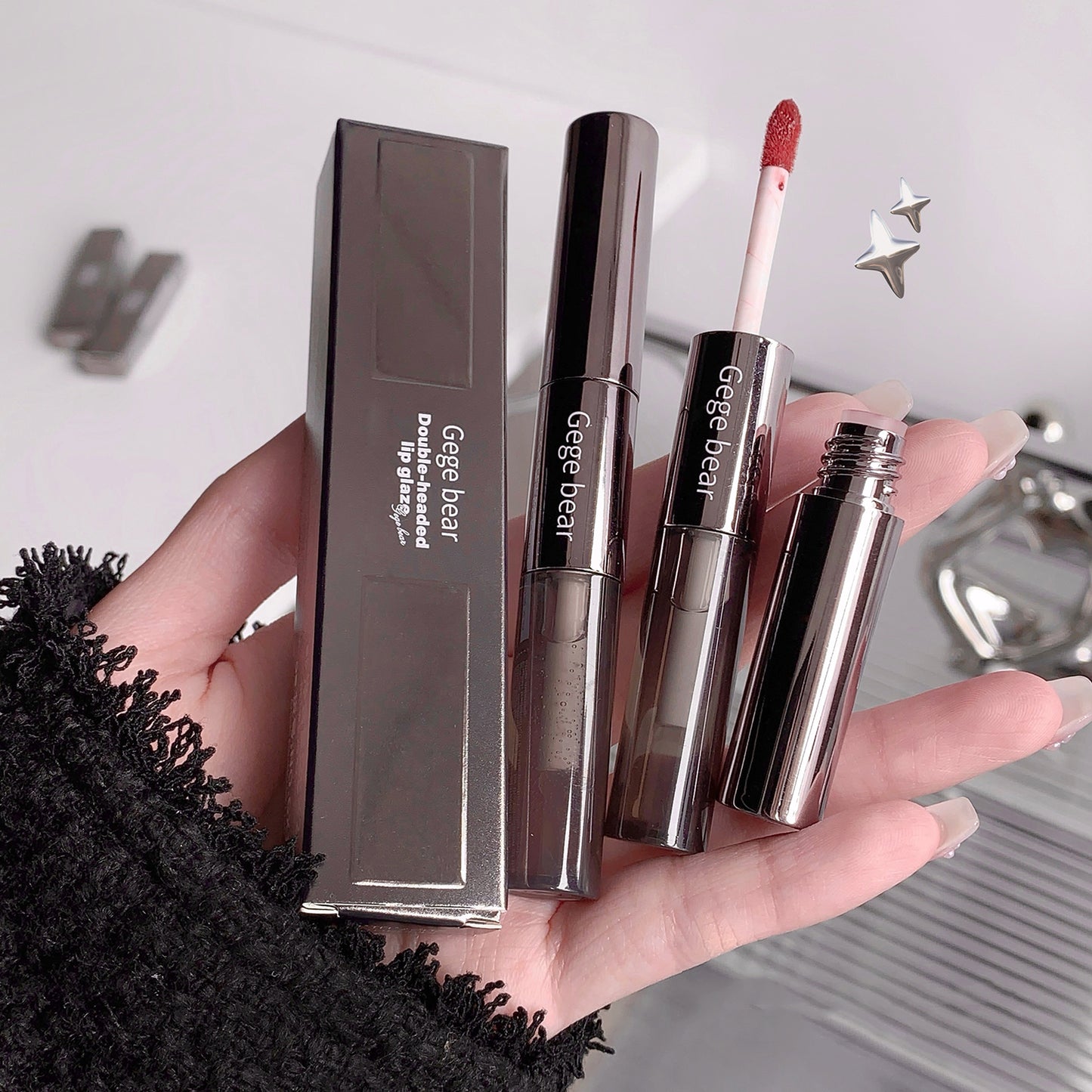 Hand holding lip products with 'Gigebear' branding against a neutral background