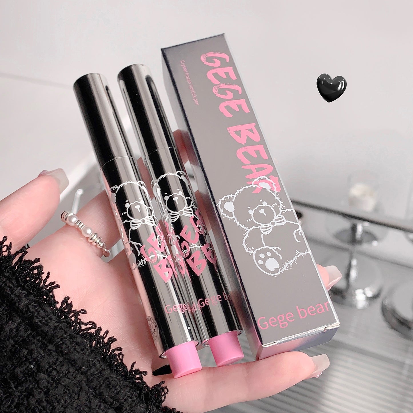 Two lip glosses with pink caps and a Gege Bear branded box on a light background.