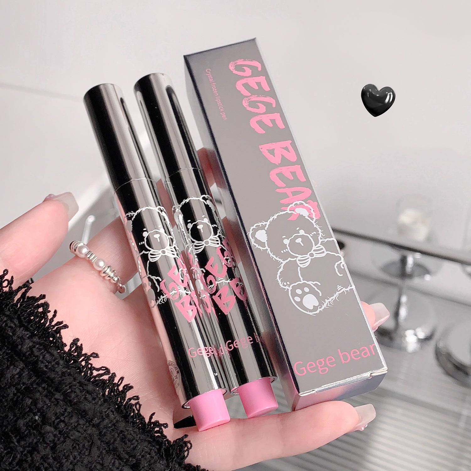 Two lip glosses with pink caps and a Gege Bear branded box on a light background.