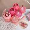 Pink lip gloss applicators with red and clear liquids, applied on a hand and lips.