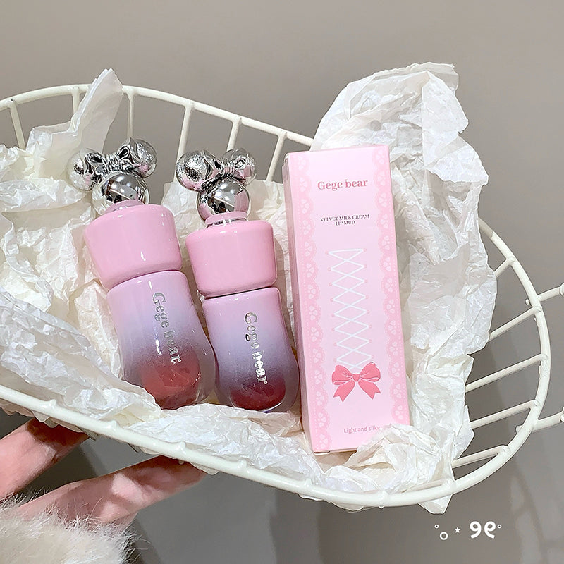Pink lip balm and its packaging on a white decorative stand.