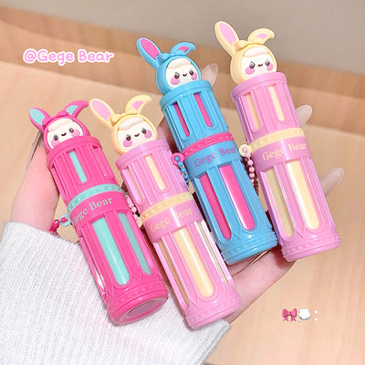 Four colorful lip balms with cartoon bear faces on a beige background