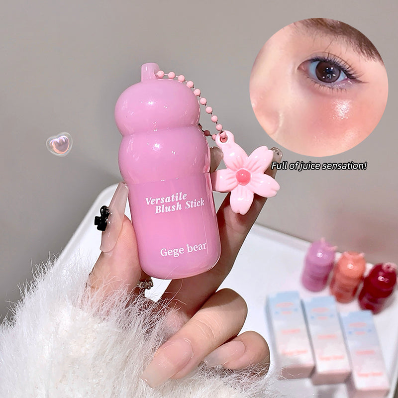 Pink blush stick with a flower charm held by a hand, close-up of blush application, and additional blush sticks in the background.