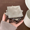 Stack of metallic square items with 'Gegebear' branding held in a hand against a brown background.
