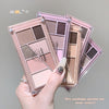 Makeup eyeshadow palette with seven colors held by a hand on a gray background