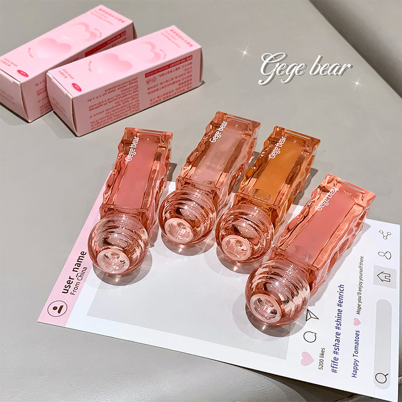 Set of pink lip glosses with packaging on a gray surface