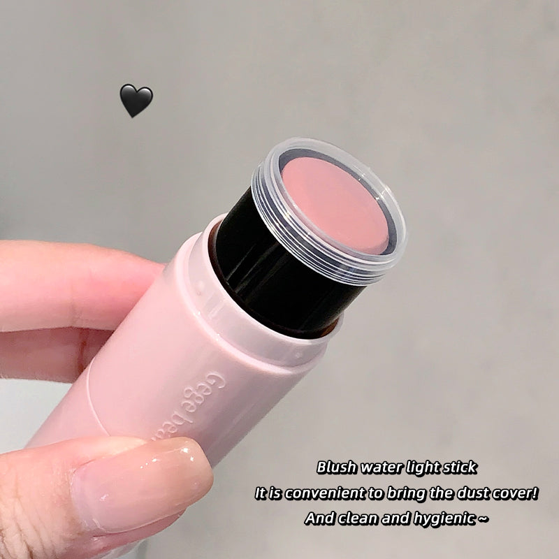 Hand holding a blush water light stick with a clear cover on a gray background