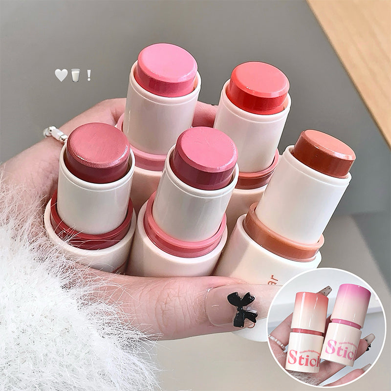 Hand holding multiple lip balm sticks with pink and red caps on a neutral background