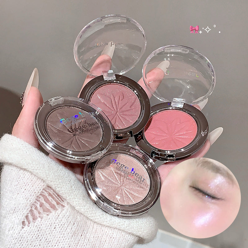 Hand holding four makeup compacts with visible blush colors on a neutral background