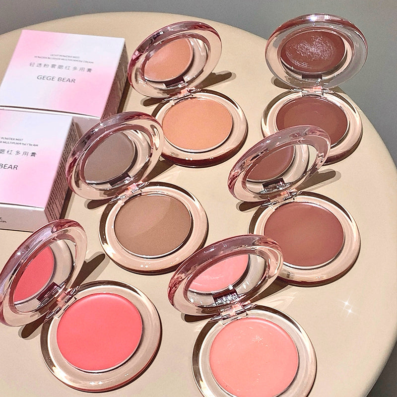 Set of makeup blushes in various colors on a round surface with a pink box in the background.