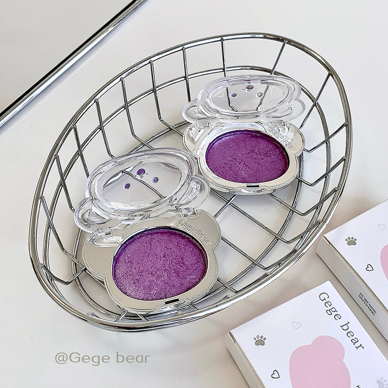 Three purple bear-shaped containers in a wire basket on a light surface.