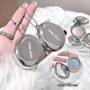 Silver compact mirror with 'Gege bear' branding held by a hand, with a blurred background of similar mirrors.