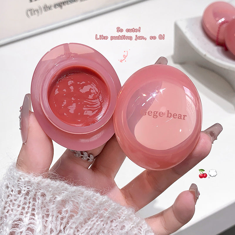 Pink lip balm with visible brand name held by a hand on a light background