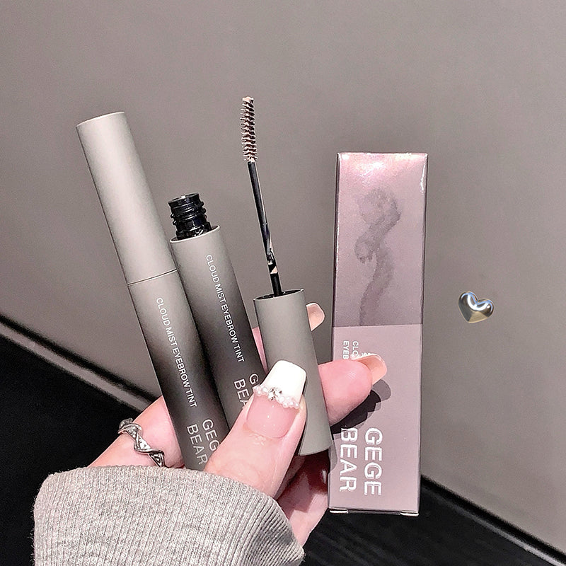 Eyebrow pencil and its packaging held by a hand against a neutral background