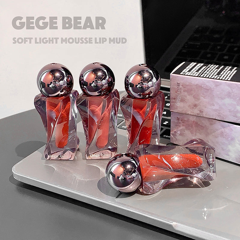 GEGE BEAR soft light mousse lip mud packaging on a reflective surface with a blurred background