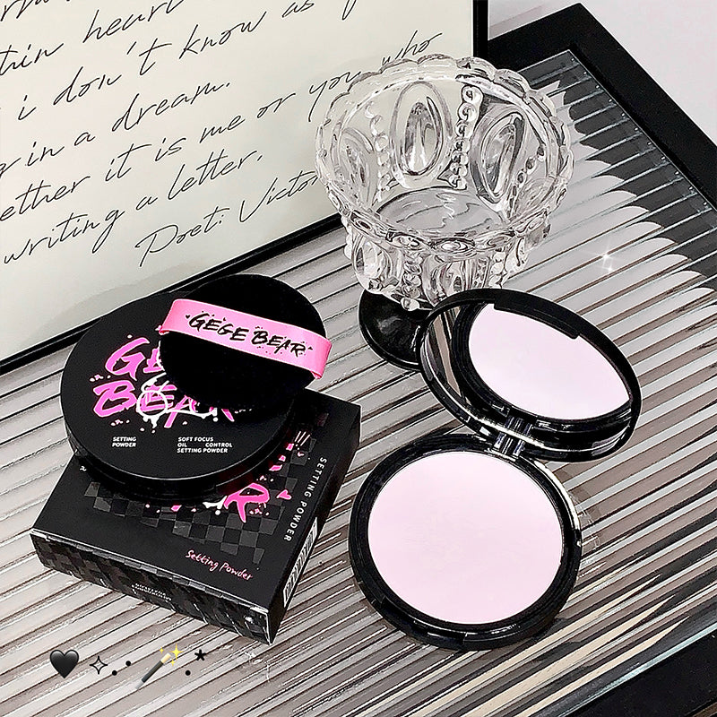 Makeup compact with pink powder and 'Gisele Bear' branding on a decorative surface.