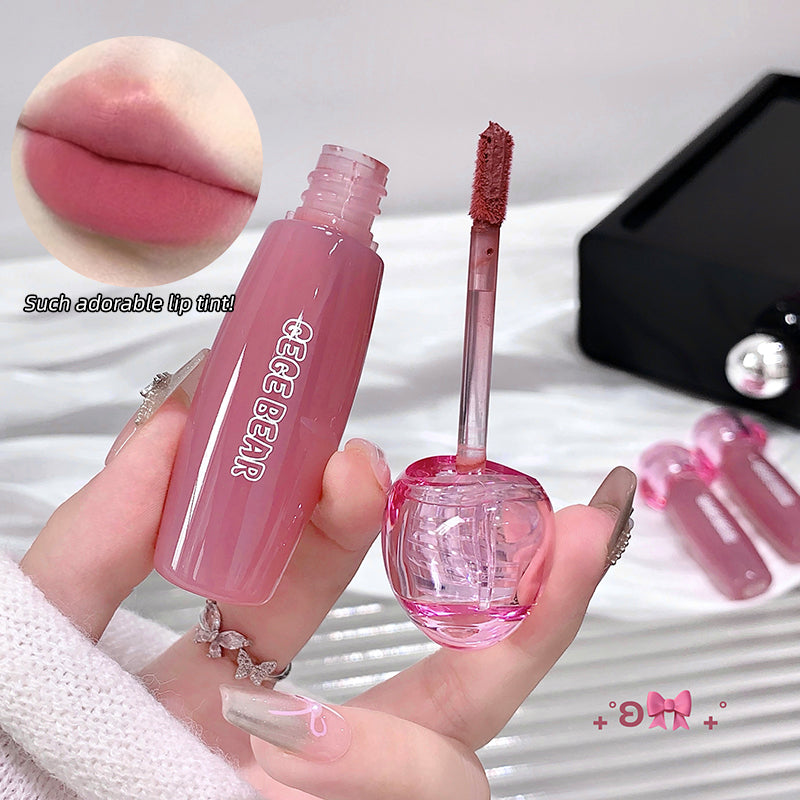 Pink lip tint with applicator held by a hand, close-up of lips shown, brand 'GEGE BEAR' visible.