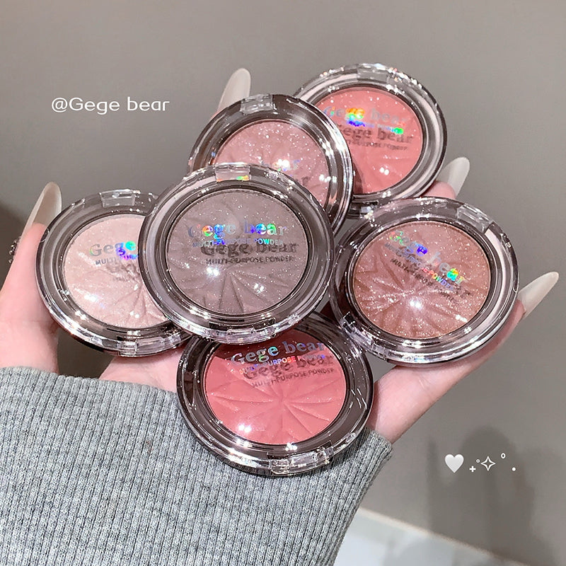 Five compact makeup products held in a hand with a neutral background