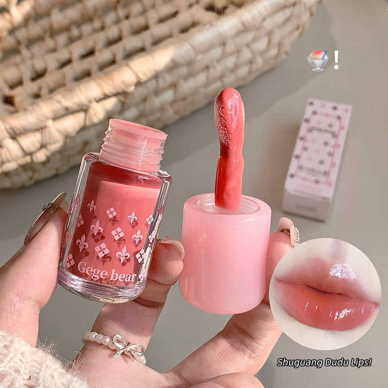 Pink lip gloss with applicator held by a hand, brand 'Gegebear' visible