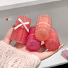 Hand holding GECE BEAR lip balms with a plain background
