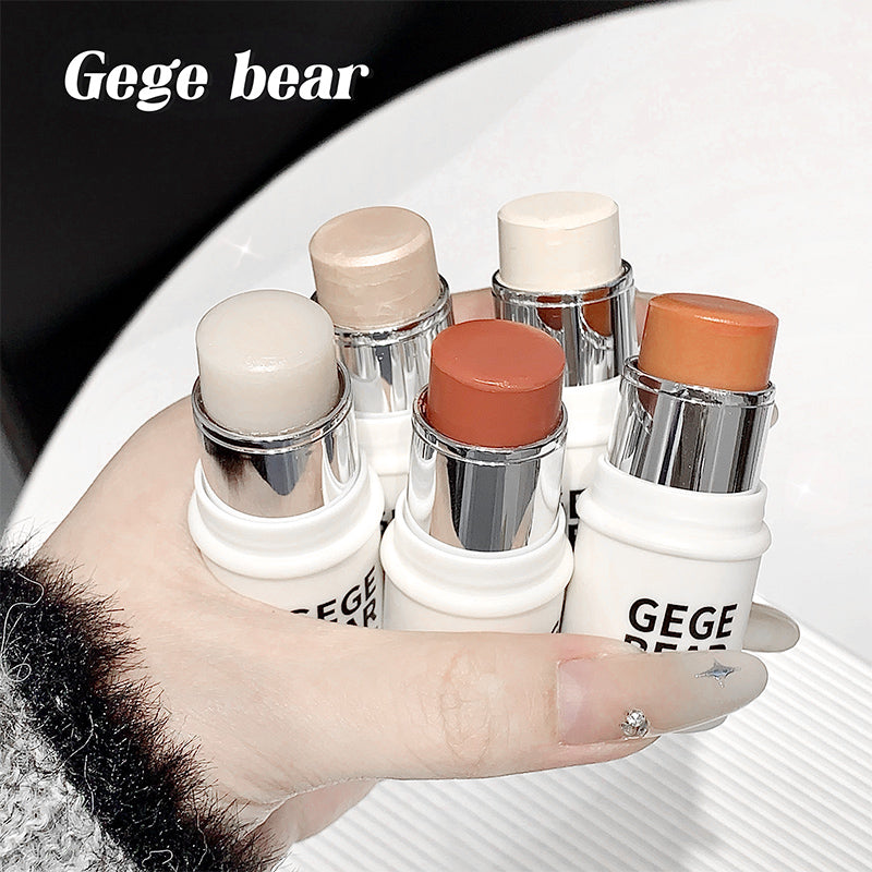 Hand holding makeup sticks with 'GEGE bear' branding on a white surface.