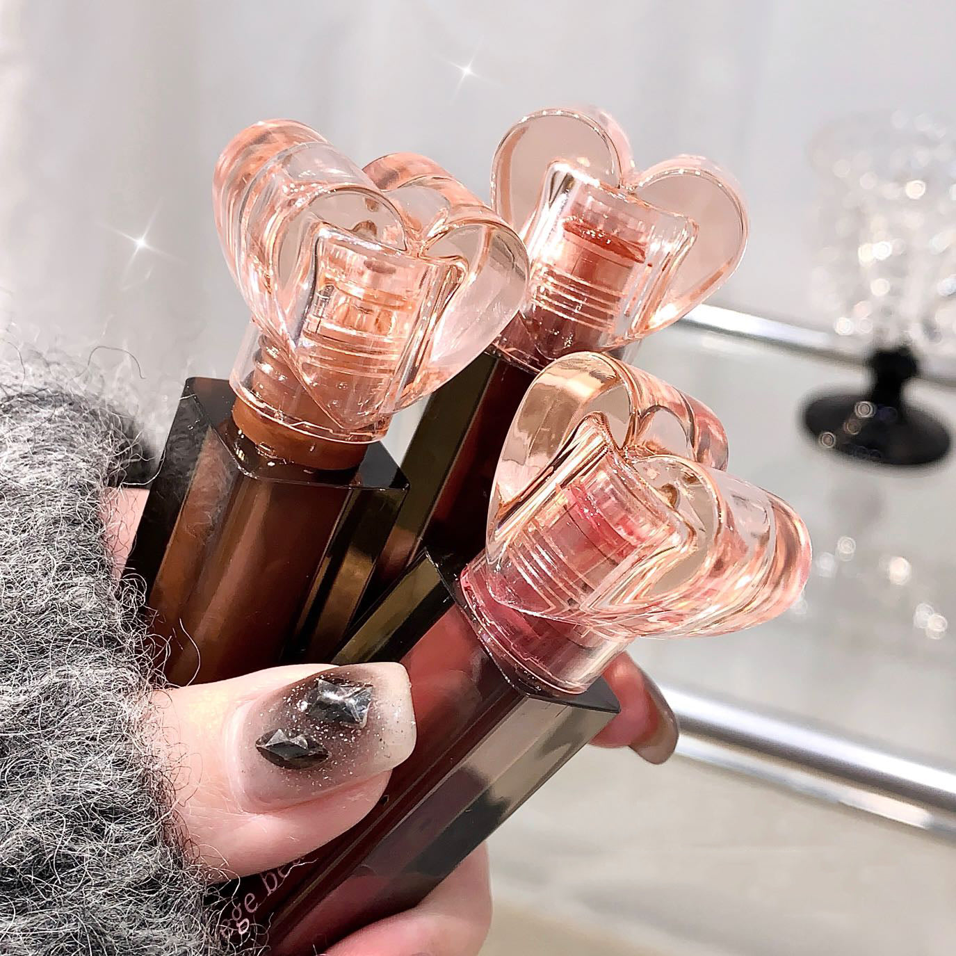 Hand holding a set of lipsticks with rose gold caps against a blurred background