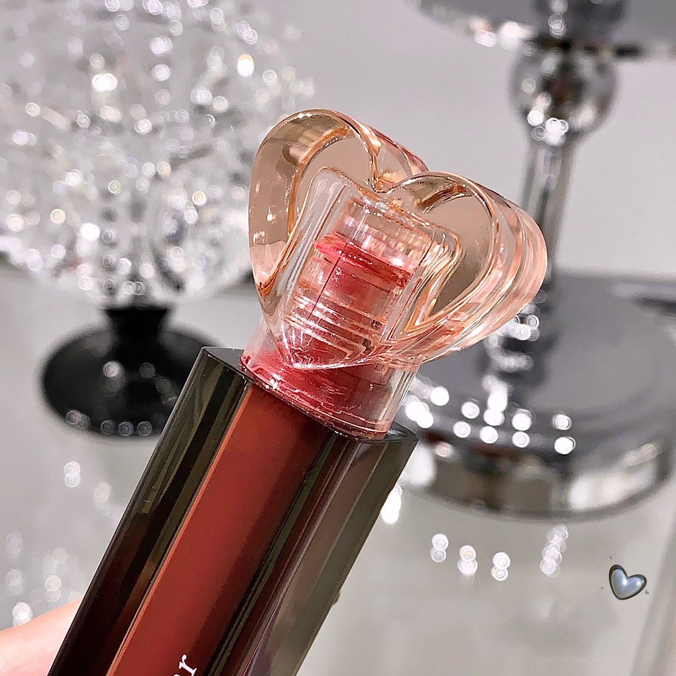 Lip balm with a heart-shaped cap on a reflective surface