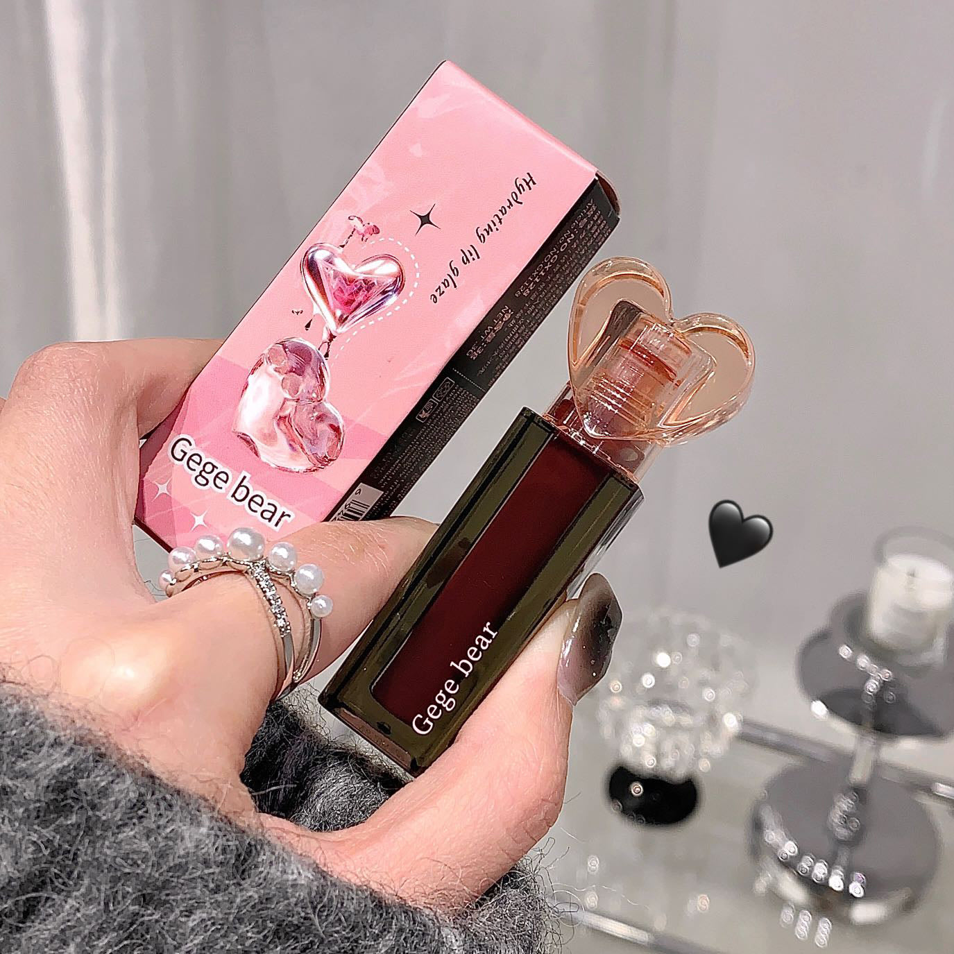 Hand holding a Gege Bear perfume bottle and packaging against a neutral background