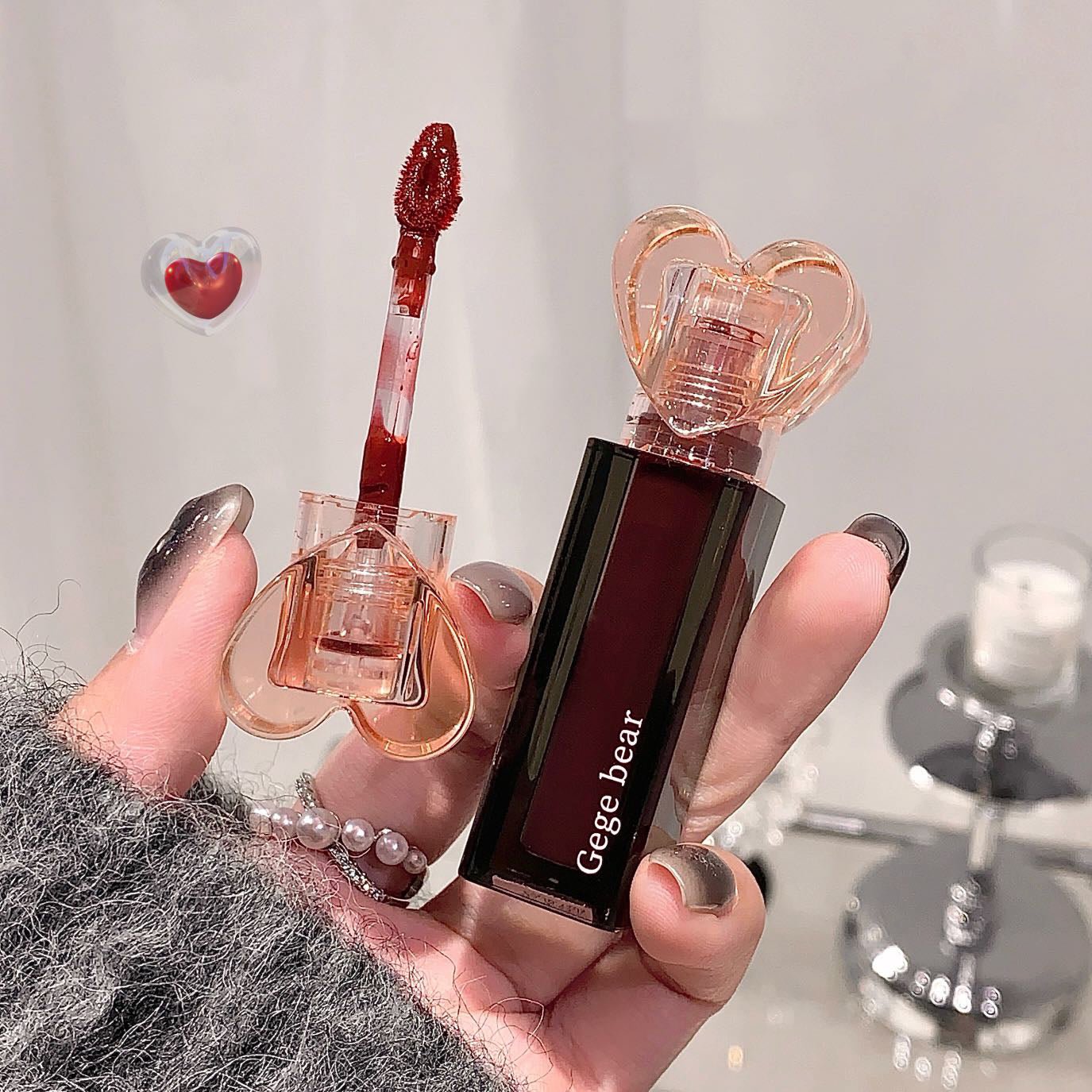 Lipstick with heart-shaped design held by a hand, brand 'Geege bear' visible