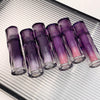 Set of purple and pink lip glosses with 'Geege bear' branding on a metallic surface.