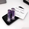 Two purple perfume bottles on a black tray with a 'Romantic Floral' card in the background.