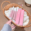 Basket with pink lip products and packaging on a textured surface