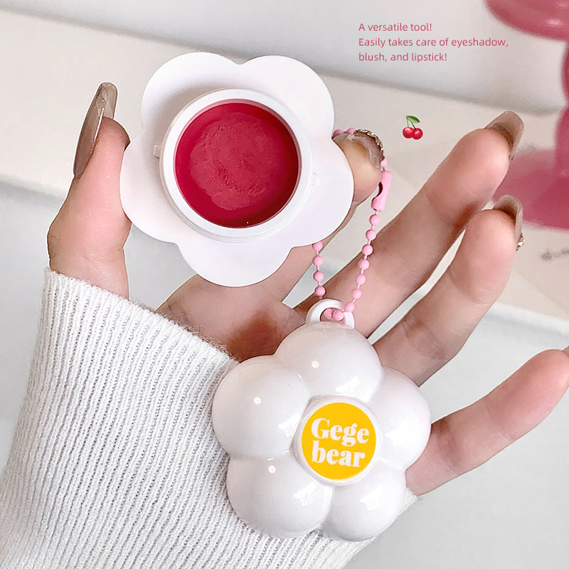 Hand holding a white cosmetic tool with pink contents, branded 'Gegebear', on a light background.