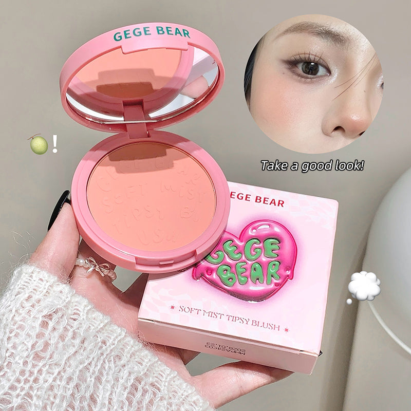Pink blush compact with open lid and packaging, held by a hand, on a neutral background.