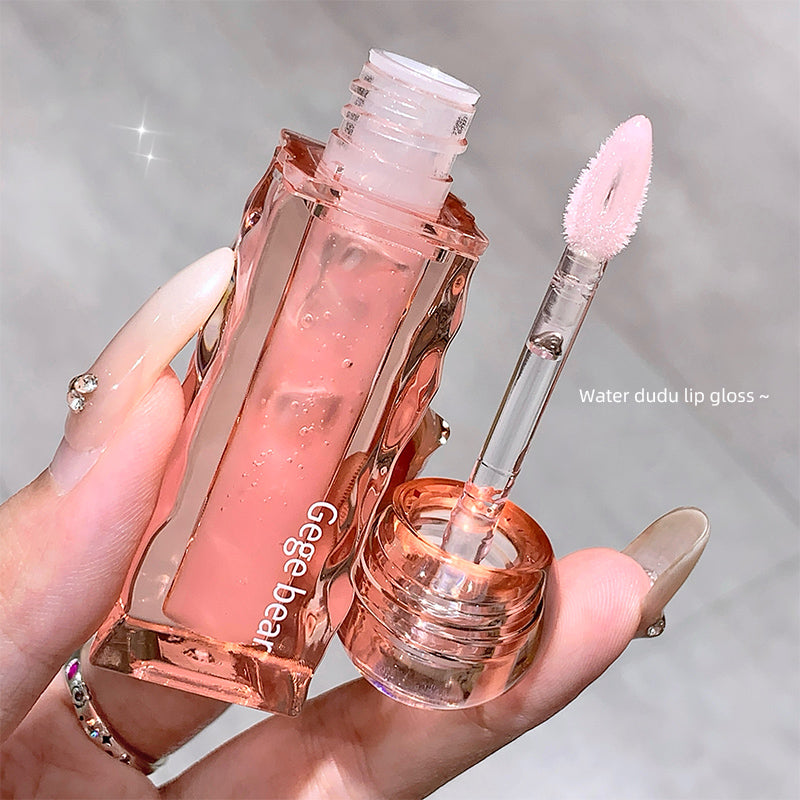 Pink lip gloss with applicator held by a hand against a neutral background