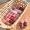 Set of pink and red nail polishes in a woven basket on a wooden surface