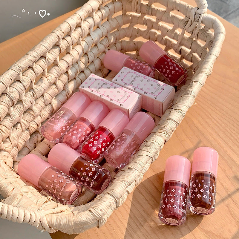 Set of pink and red nail polishes in a woven basket on a wooden surface