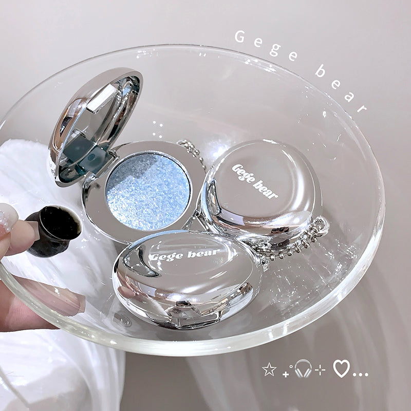 Makeup compact with 'Gege bear' branding on a clear stand.