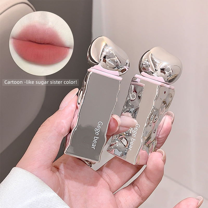 Two silver lip glosses held in a hand with a close-up of lips and text 'Cartoon-like sugar sister color' on a blurred background.