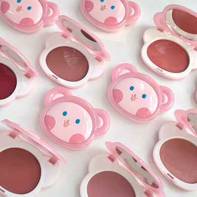Pink makeup products with bear designs on a white background