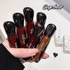 Hand holding multiple bottles of 'Gege bear' lip gloss with a blurred background