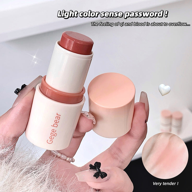Hand holding a Gege bear makeup stick with close-up of color swatch on a light background