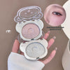 Compact mirror with glittery makeup on a neutral background