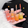 Hand holding two lip oil products with visible branding against a black background