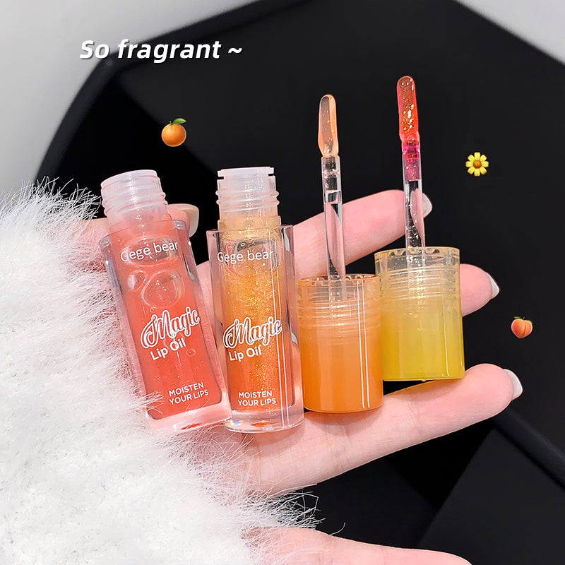 Hand holding two lip oil products with visible branding against a black background